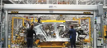 ?? ─ Bloomberg ?? Hard drive: Employees assemble components of the BMW Series 3 vehicle in Mexico. BMW and other automakers have been forced to halt production due to chip shortages, a factor that could push up inflation.