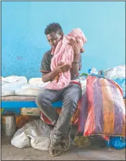  ??  ?? Tigrayan Goytom Tsegay, 19, tries to comfort his 4-month-old niece, Turfu, in the family’s shelter in Hamdayet. “I spend the whole day with them. My favorite part is feeding them. I’ve decided to stay with them all their lives.”