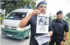  ?? AFP ?? A police officer holds a leaflet bearing a portrait of Nora Quoirin at a checkpoint during a search and rescue operation.