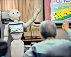  ??  ?? A new approach to ageing: Japan’s elderly residents can choose from a host of activities to keep them mentally and physically well, from mimicking a robot, above, to sorting crockery, enjoying origami or cuddling a therapeuti­c robot seal