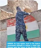  ??  ?? KIRKUK: An Iraqi fighter loyal to the federal government attempts to remove a metal sign painted with the colors of the Kurdish flag from a building in the multi-ethnic northern Iraqi city of Kirkuk.