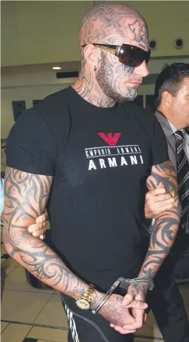  ??  ?? Brett "Kaos" Pechey is escorted by police at Brisbane Internatio­nal Airport in 2015 after his return from Thailand.