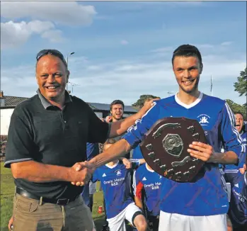  ?? 01_B36footy02 ?? Brodick captain Matthew Dobson receives the Arrran Dairies shield from dad Alastair.