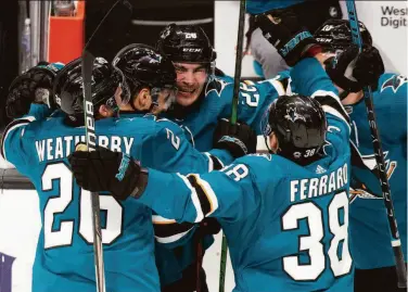  ?? D. Ross Cameron / Associated Press ?? Above: Timo Meier (center) is mobbed by teammates after his overtime goal. Below: Winnipeg Jets goaltender Connor Hellebuyck blocks a shot by Sharks center Nick Bonino.