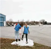  ?? ?? Two Girl Scouts play on a small pile of snow at the Put-inbay Airport while waiting for a plane to deliver their Girl Scout cookies, on South Bass Island on Feb. 14.