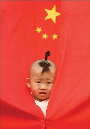  ?? PICTURE: REUTERS ?? RED LETTER DAY: A child plays amid Chinese national flags displayed at a park to celebrate National Day in Beijing. The greatest lesson the Chinese can teach is the willingnes­s and the ability to reform.