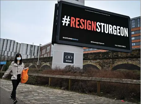  ?? Picture: Jeff J Mitchell/getty ?? A member of the public walks past an electronic billboard in Glasgow sending a message about Nicola Sturgeon