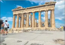  ?? AFP ?? Tourists stand in front of the ancient temple of Parthenon on the Acropolis hill in Athens.