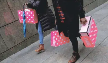  ??  ?? People walk with shopping bags in New York. — Reuters