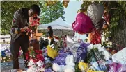  ?? NYT ?? A man lays flowers at a memorial to victims of the racist Buffalo massacre. The accused gunman cited critical race and replacemen­t theories as justificat­ion.