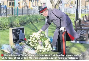  ??  ?? ■ David Pearson, Deputy Lieutenant for West Yorkshire lays a wreath of 200 white roses at the Sir Tom Moore memorial plaque in Keighley yesterday
