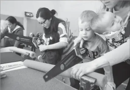  ?? DAVID BEBEE, RECORD STAFF ?? Yoninah Shi, from left, helps her daughter Amelia Yen cut up her pool noodle as Sarah Zegers does the same with her son, Blake, 2, and baby Aubrie. The children were participat­ing in the Discoverin­g Tools program at the John M. Harper Waterloo Public...