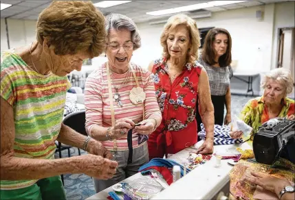  ?? PHOTOS BY JAMES WOOLDRIDGE / THE PALM BEACH POST ?? Sue McLean (from left), Lois Behrend, Marion McIntire and others with the Sand Dollars Quilting Bee sew fidget pillows, which will be donated to Specialize­d Adult Day Centers operated by Alzheimer’s Community Care, last month at the North Palm Beach Public Library. “It gives you satisfacti­on that you’re giving to others and using your skills to make a difference,” Behrend says.