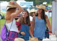  ?? PETE BANNAN – DIGITAL FIRST MEDIA ?? Jill Arrowsmith of Downingtow­n, with friends Grace Hollis and Grace Poluch of Chester Springs, look for the perfect cowboy hat at the Citadel Country Spirit USA Festival at Ludwig’s Corner show grounds Saturday.