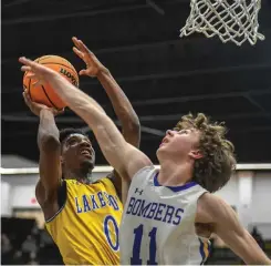  ?? The Sentinel-Record/Grace Brown ?? Lakeside’s Caleb Campbell (0) goes up for a basket as Mountain Home’s Reed Ellison (11) defends during Wednesday’s first-round game in the Class 5A state basketball tournament at Trojan Arena. The Bombers defeated the Rams, 57-46.