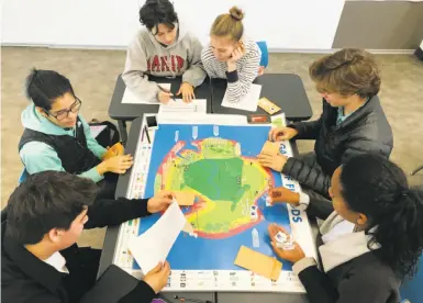  ?? Marin County Community Developmen­t Agency ?? Seniors at Marin Academy in San Rafael weigh priorities in a dire climate-change scenario as they play Game of Floods in class. The board game presents a future Marin County is likely to face — and not only Marin.