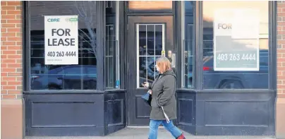  ?? REUTERS ?? A woman walks past a For Lease sign at a retail building in Calgary.