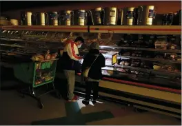  ?? LM OTERO — THE ASSOCIATED PRESS FILE ?? Customers use the light from a cell phone at a grocery store in Dallas last month after a winter storm left millions without power in the state.