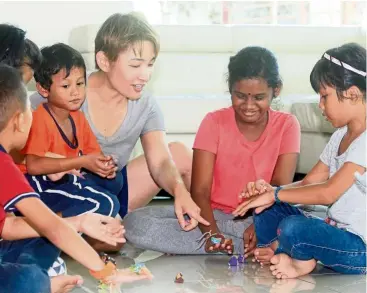  ??  ?? Chong (third from right) taught the children at the Taman Megah home how to play batu Seremban.