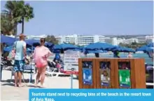  ??  ?? Tourists stand next to recycling bins at the beach in the resort town of Ayia Napa.