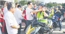  ?? ?? KESELAMATA­N: Lee (dua kiri) membantu menyarungk­an topi keledar kepada salah seorang penunggang motosikal pada kempen tersebut.