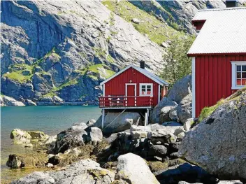  ?? FOTO: INSA KOHLER/DPA ?? Blick auf den Ort Reine auf den Lofoten: Spitze Felsen und rote Fischerhüt­ten am Meer.