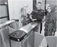  ?? HANUNG HAMBARA/JAWA POS ?? LEBIH SELEKTIF: Petugas linmas Purba A. dan Dwi Suryaning, pegawai dinas cipta karya, mencoba keluar dari gate di kantor mereka.