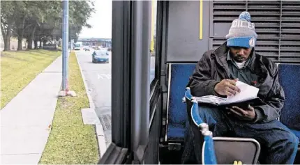  ?? Karen Warren photos / Houston Chronicle ?? Jerome Edmond, a 34-year-old Army veteran, checks his homework as he rides his third bus before a mile hike to campus.