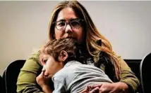  ?? ?? Natalia Fernandez holds her daughter Camila Briones, 3, as she listens to a discussion Saturday about the state takeover.