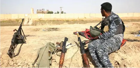  ??  ?? A member of the Iraqi forces sits on a river bank across from Kurdish peshmerga positions on the outskirts of Kirkuk in this file photo. (AFP)