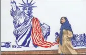  ?? AP ?? A woman walks past a satirical drawing of a crumbling Statue of Liberty on the wall of the former US embassy in Tehran.