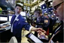  ?? RICHARD DREW — THE ASSOCIATED PRESS ?? Specialist Thomas McArdle, left, works with traders John Panin, center, and Jeffrey Vazquez on the floor of the New York Stock Exchange Monday.