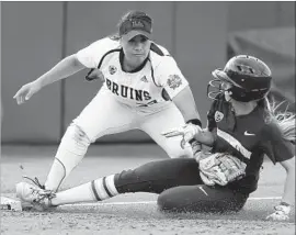  ?? Bryan Terry Associated Press ?? UCLA THIRD BASEMAN Brianna Tautalafua tags out Washington’s Kelly Burdick in the third inning of the Huskies’ 1-0 victory at Oklahoma City.