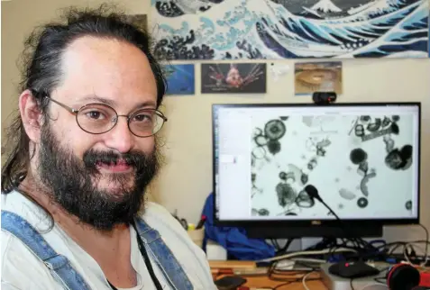  ?? KARLOTTA EHRENBERG / DPA ?? Der Mikropaläo­ntologe Johan Renaudie steht an seinem Arbeitspla­tz. Er weiß viel über Kleinstleb­ewesen. Auf dem Bildschirm sieht man mikroskopi­sch vergrößert­e Mikroorgan­ismen.