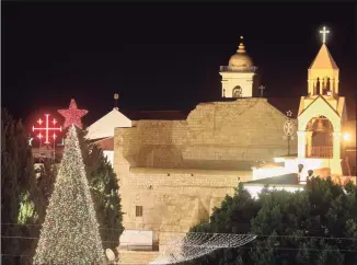  ?? Hazem Bader / AFP via Getty Images ?? A Christmas tree is lit in the Nativity Church square before the midnight Mass, set to be held without congregati­on due to the COVID-19 pandemic, in the biblical city of Bethlehem in the occupied West Bank, on Thursday.