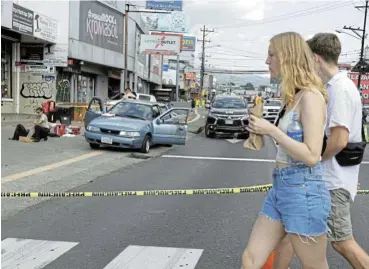  ?? /Reuters ?? Firm hand: Tourists walk by a scene where unknown assailants opened fire and wounded two people travelling in a car, in San Jose, Costa Rica. President Rodrigo Chaves is pushing for a radical shift in the way the country deals with violent crime.