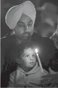  ?? ASSOCIATED PRESS ?? Pushpinder Singh holds his 2-year-old son, Prannveer, during a candleligh­t vigil at the Sikh Temple of Wisconsin on Aug. 5, 2013, in Oak Creek. A white supremacis­t killed six people at the temple during a shooting rampage in 2012.