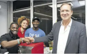  ?? ?? Deaf Can! barista Dimel Ballen (left) received a congratula­tory handshake from S Foods CEO Christophe­r Issa (right) as fellow baristas Mellisa Thompson and Javanniw Dawes shared in the special moment.