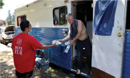  ?? Photograph: Karen Ducey/Reuters ?? The Salvation Army’s Shanton Alcaraz gives bottled water to resident Eddy Norby, and invites him to a nearby cooling center during a heat wave in Seattle, Washington, on 27 June 2021.