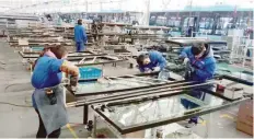  ?? — AFP ?? Workers building parts for an electric bus at a factory in Liaocheng, in China’s eastern Shandong province.