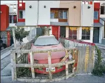  ?? Don Bartletti Los Angeles Times ?? A FENCED-IN CAR sits in the frontyard of a home in the Cañadas del Florido developmen­t in eastern Tijuana.