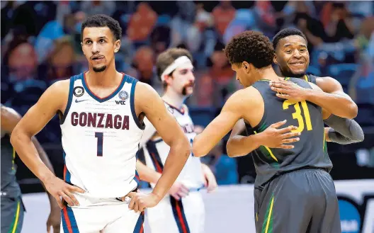  ?? JAMIE SQUIRE/GETTY ?? Baylor’s MaCio Teague, right in foreground, hugs teammate Jared Butler as Gonzaga’s Jalen Suggs shows his frustratio­n during the NCAA championsh­ip game Monday in Indianapol­is.