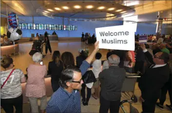  ?? PHOTO ?? John Wider holds up a sign becoming Muslims in the Tom Bradley Internatio­nal Terminal at Los Angeles Internatio­nal Airport on Thursday in Los Angeles. AP