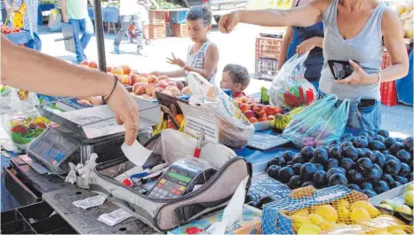  ?? FOTO: DPA ?? Ein griechisch­er Landwirt verkauft in Athen auf einem Wochenmark­t sein Obst und Gemüse. Die Händler haben kleine, portable Registrier­kassen dabei, um Belege aushändige­n zu können und nicht ins Visier der Steuerfahn­der zu gelangen.