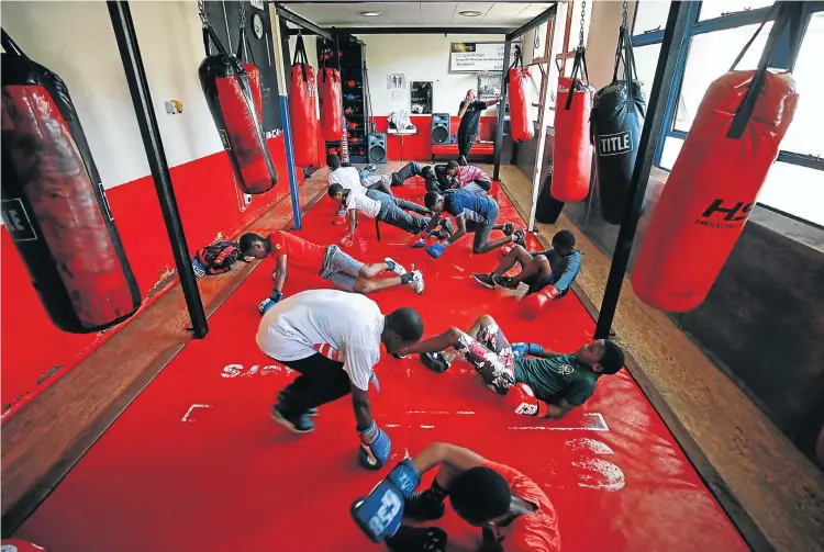  ?? Pictures: Alaister Russell ?? Former boxer Anton Gilmore, below, gives youngsters some tips during a training session at the Fight With Insight gym in Parktown, Johannesbu­rg. Among the NGO’s aims is to provide a safe place for children like those above who might need help channellin­g aggression and frustratio­n into harmless outlets.