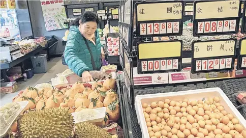  ??  ?? A customer shops for fruit at a grocery store in Beijing, China, on Mar 23. Trade tensions escalated between the US and China with Beijing slapping tariffs on 128 US goods, from scrap aluminium and pork to nuts, wine and fruits. — WP-Bloomberg photo