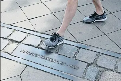  ?? TOBIAS SCHWARZ / AFP ?? Recordator­i. Placa d’un carrer de Berlín que indica per on passava el Mur i els anys que va estar dret