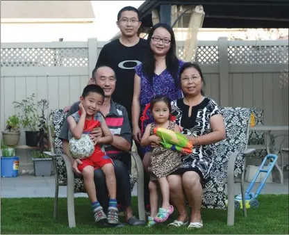  ?? The Canadian Press ?? Jiang and her husband, Jianqiao Sun, back row, stand as grandparen­ts Youfang Jiang and Li Zhang sit with grandson Sunny Jiang and granddaugh­ter Jenny Sun in the backyard of their home in Ottawa. The family immigrated to Canada from China and live...