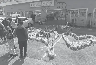  ?? BRAD HORRIGAN/HARTFORD COURANT ?? Mourners gather at a memorial for Jaqhawn Walters at the corner of Main and Rosemont Streets last month. Candles in the memorial form the letters“JQ”with two hearts.