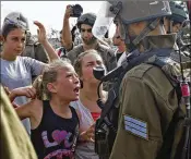  ?? AP 2012 ?? Ahed Tamimi, as a 12-year-old, raises a clenched fist toward a soldier towering over her in 2012, one of her several highly publicized run-ins with soldiers.